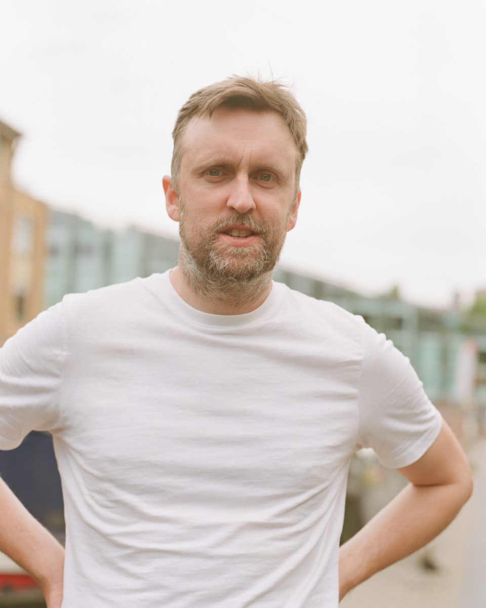 Stand-up comedian Matt Winning, who went from climate science to climate comedy. Pictured outdoors in a white t-shirt, looking a little indignant. Photo: Kid Circus