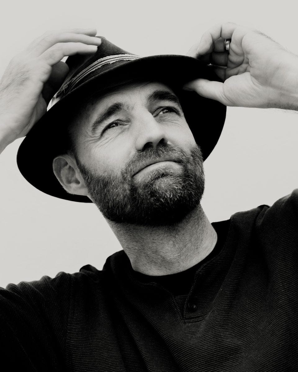 Black-and-white portrait of Thor Pedersen adjusting his hat.