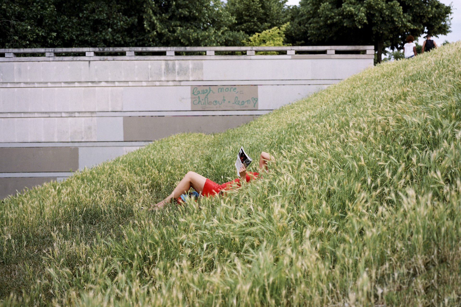 woman laying in tall grass relaxing and reading a magazine