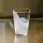 an empty glass that use to contain plant based milk standing on a table