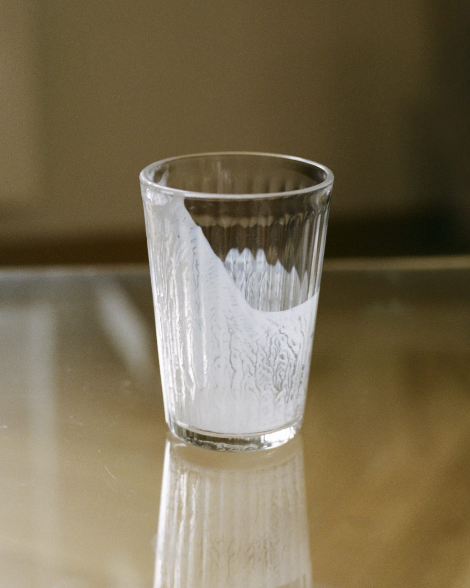 an empty glass that use to contain plant based milk standing on a table