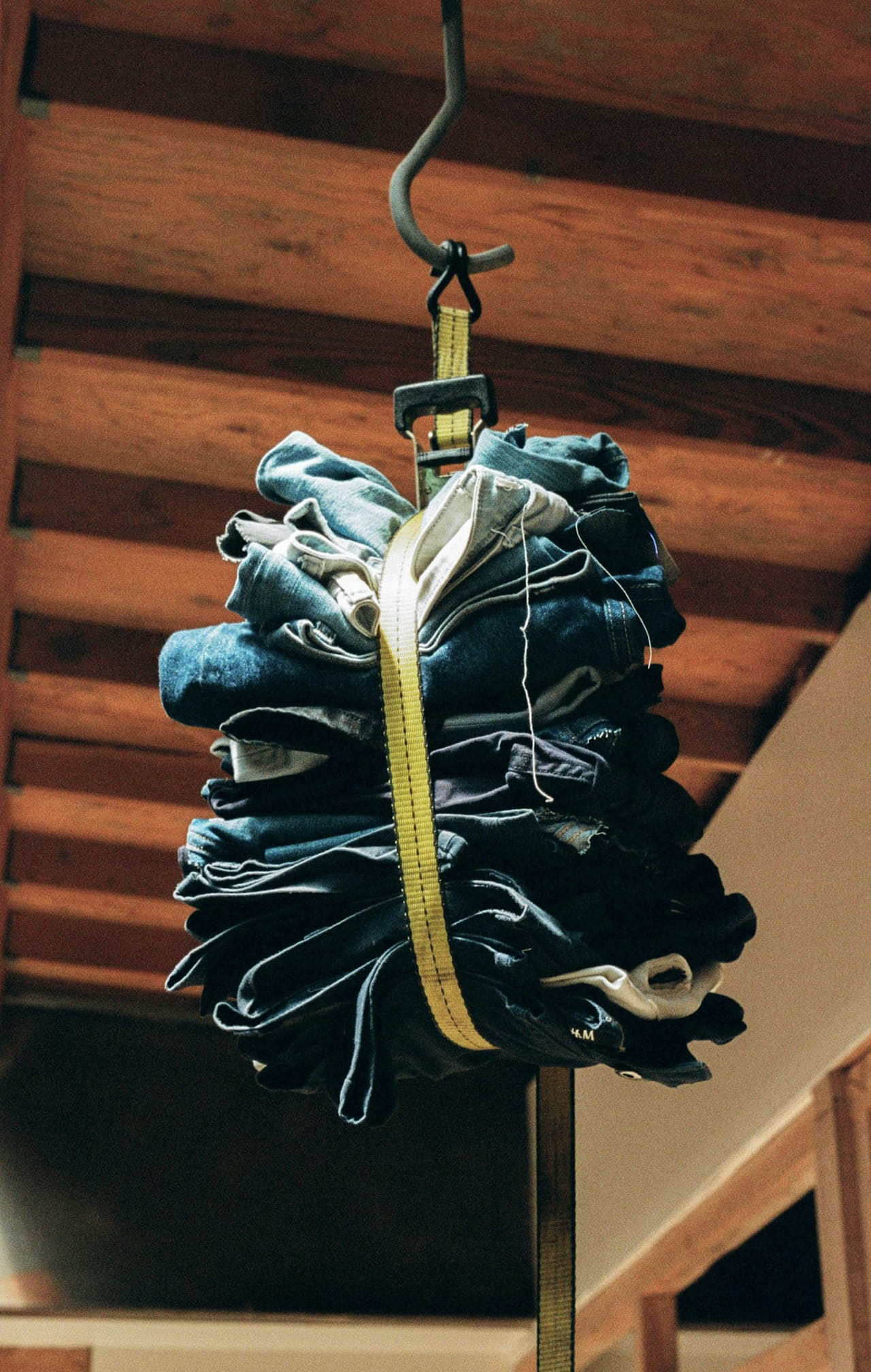 Folded slow fashion denim jeans strapped together hanging from the ceiling