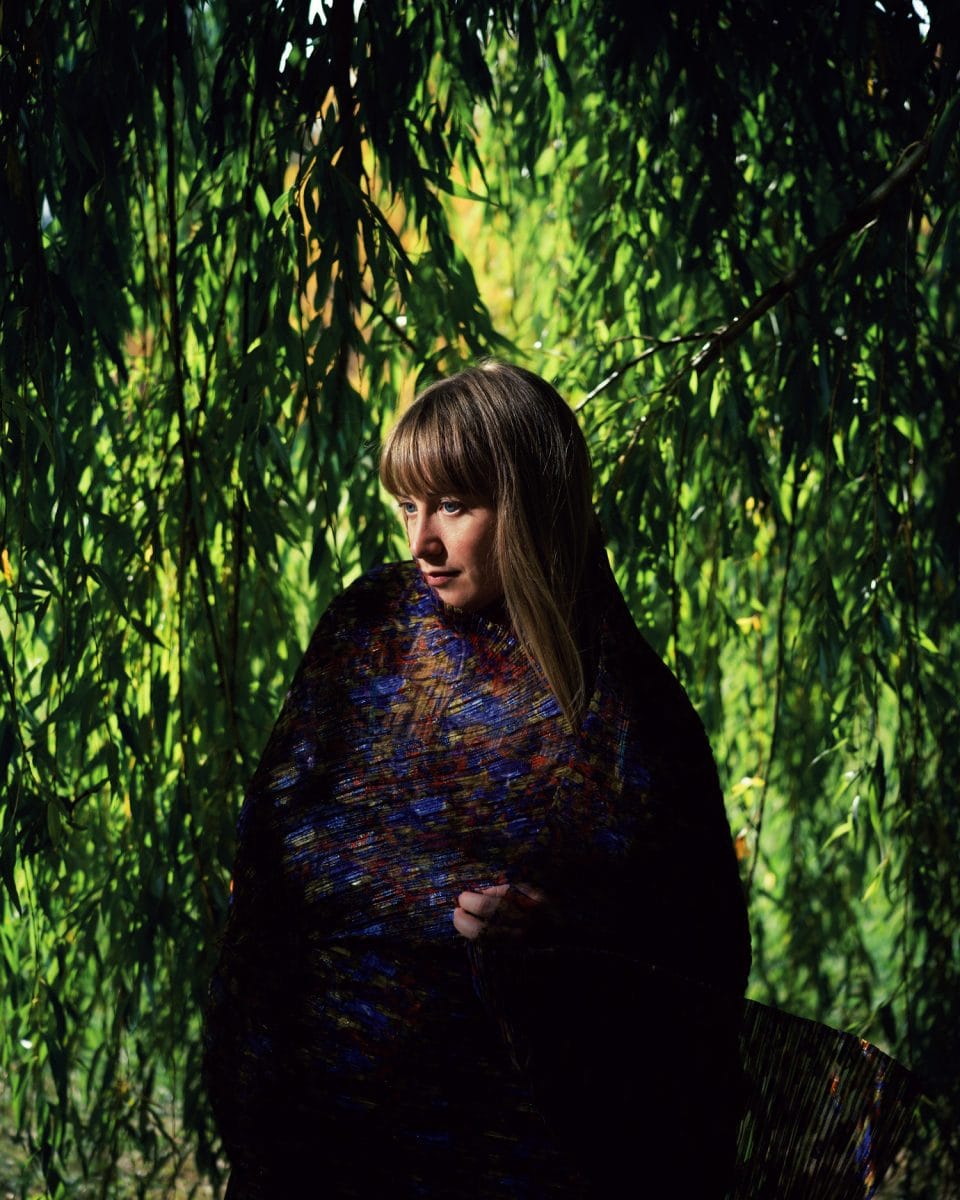 Tamara Lindeman of The Weather Station wrapped in a veil with green leaves as backdrop