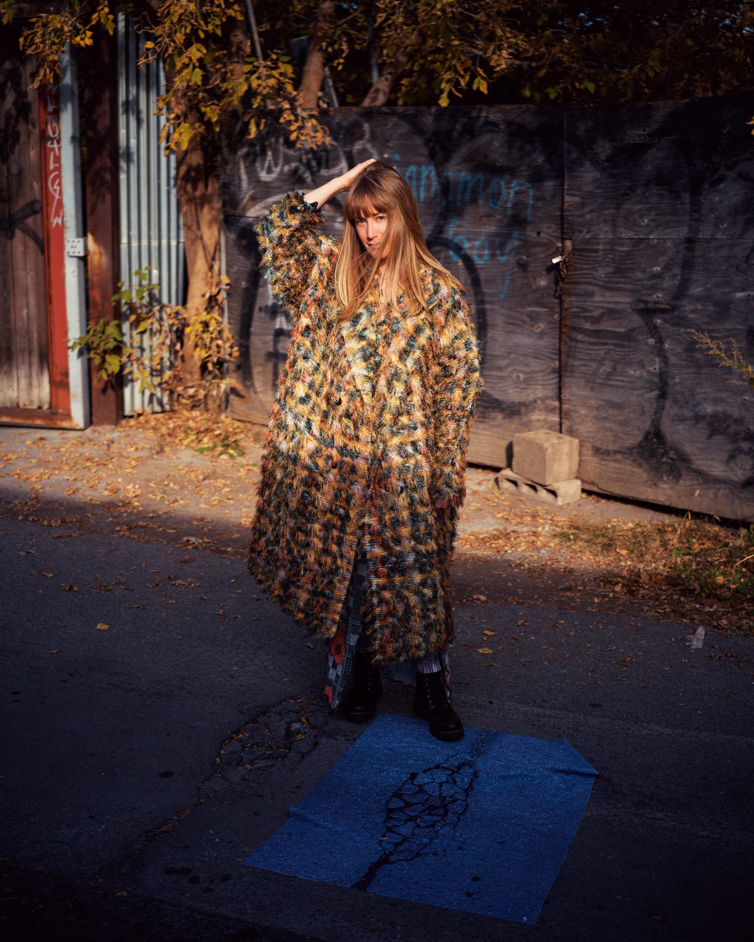 Tamara Lindeman of The Weather Station standing on a street with graffiti on a wall in the background