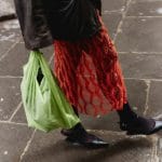 A woman walks wearing a leather jacket and red dress while carrying a plastic shopping bag. Sometimes we buy stuff without even thinking about it, and stopping that habit isn't easy.