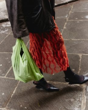 A woman walks wearing a leather jacket and red dress while carrying a plastic shopping bag. Sometimes we buy stuff without even thinking about it, and stopping that habit isn't easy.