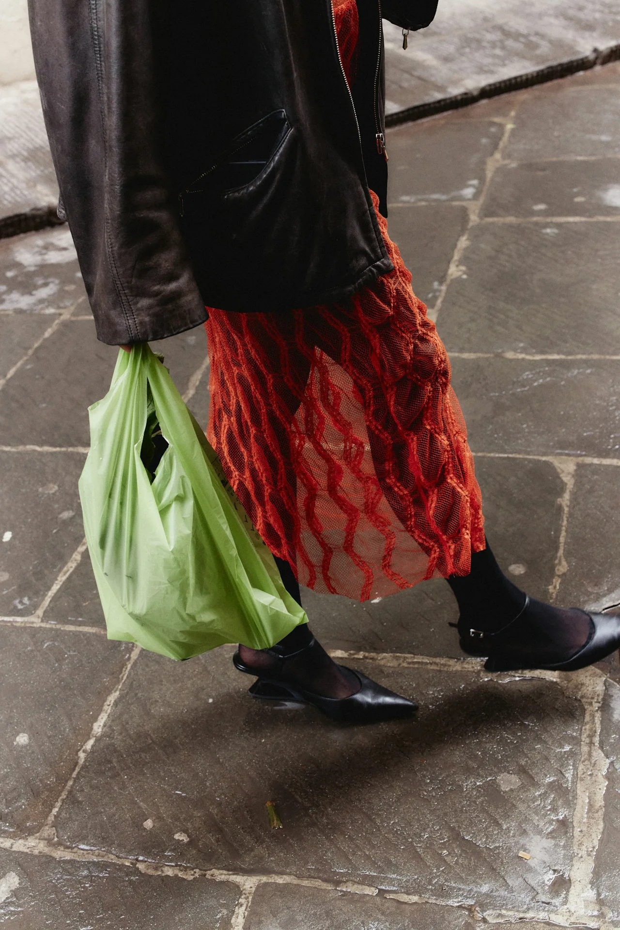 A woman walks wearing a leather jacket and red dress while carrying a plastic shopping bag. Sometimes we buy stuff without even thinking about it, and stopping that habit isn't easy.