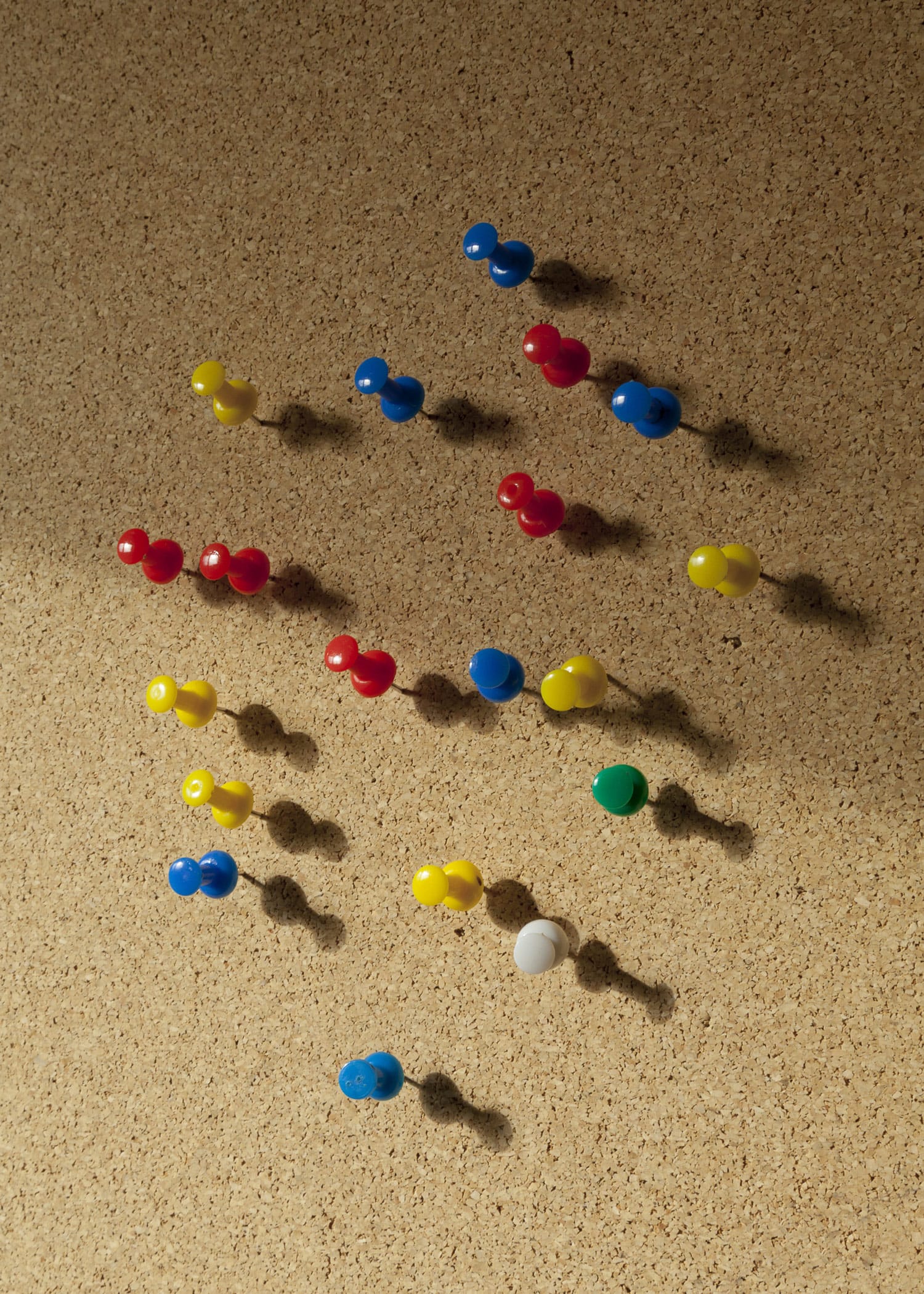 A pin board made of cork with different colored pins in it