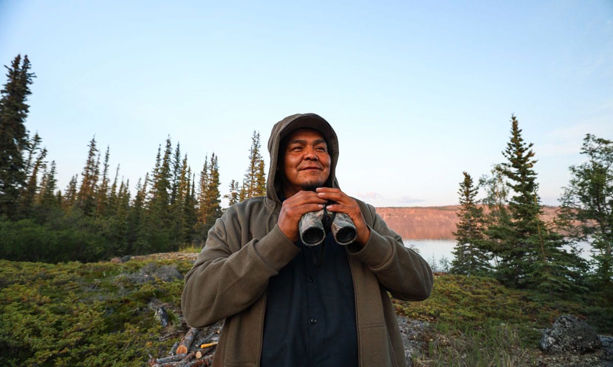 A person standing with binoculars looking into the distance. Nature documentaries often focuses on people affected by changes to their environment.