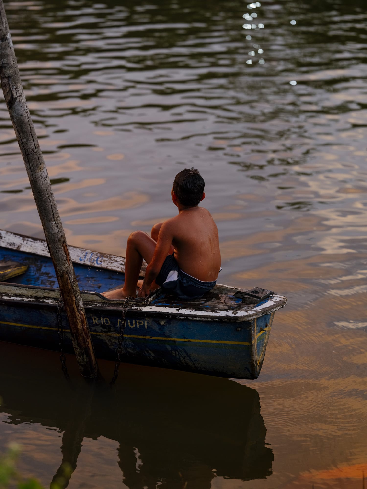 Boy sitting on a boat looking across the river