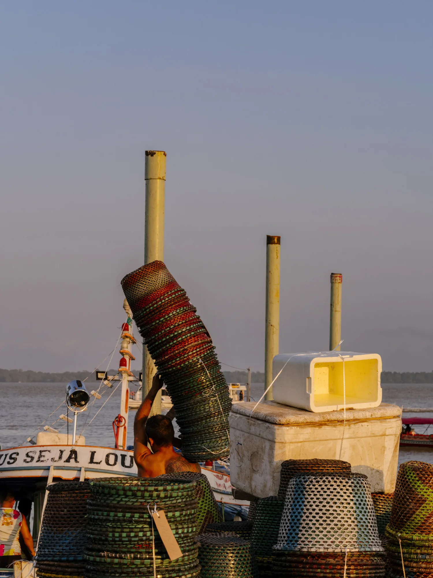 A man carries the empty baskets to one of the boats that transport the açaí.